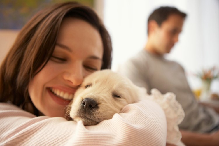 A woman hugging a puppy with a smile on her face