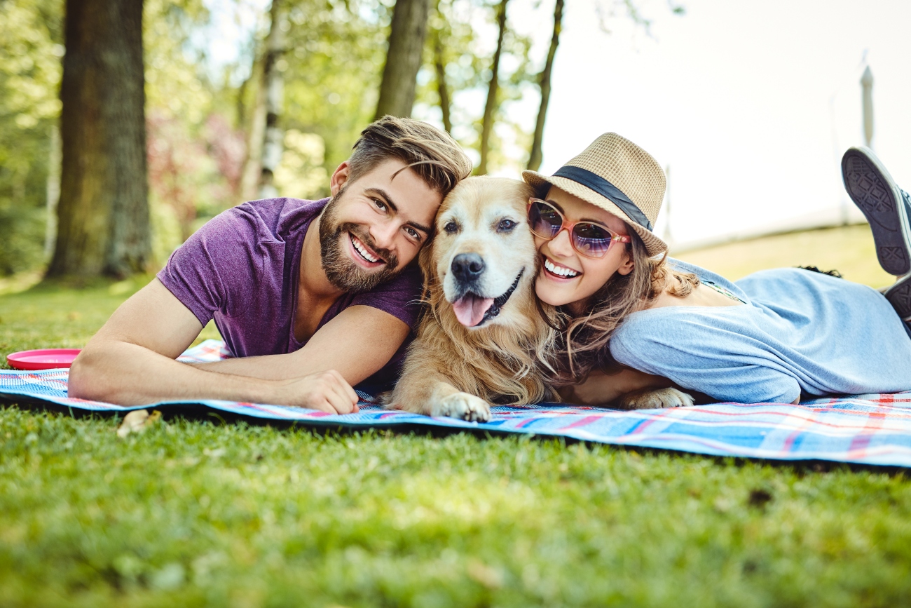 couple lying on a field with their dog in between