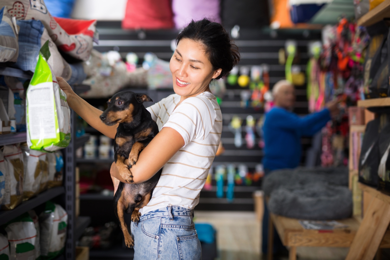 woman buying dog food whilst holding dog