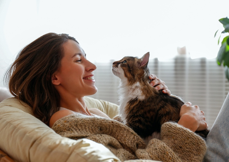 Sweet cat lying on woman's chest being stroked by happy woman
