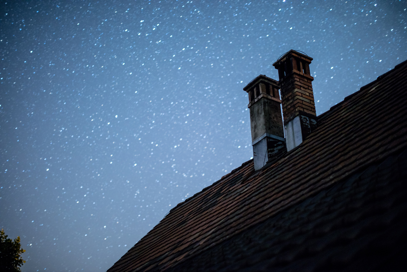 Two chimneys on the roof of a house against a starry sky