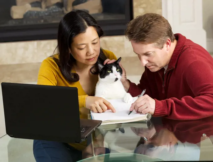 2 adults teaching a cat to write
