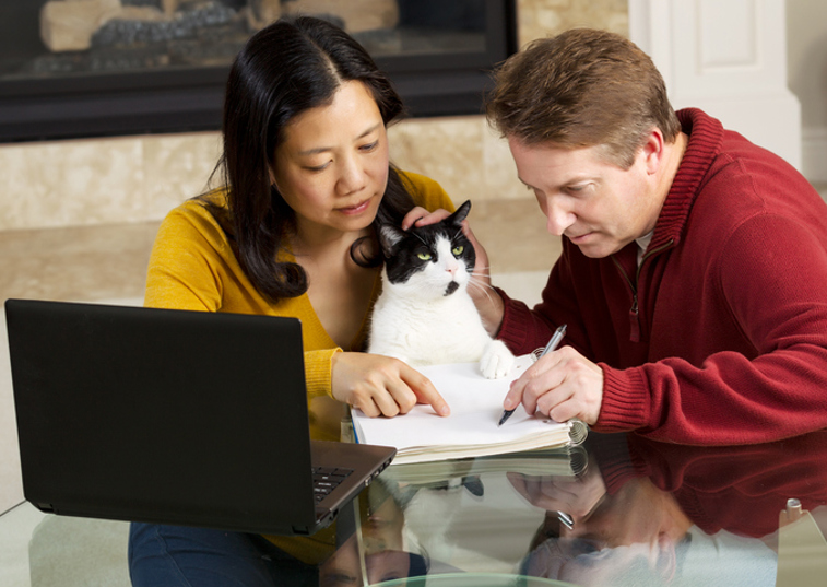 2 adults teaching a cat to write