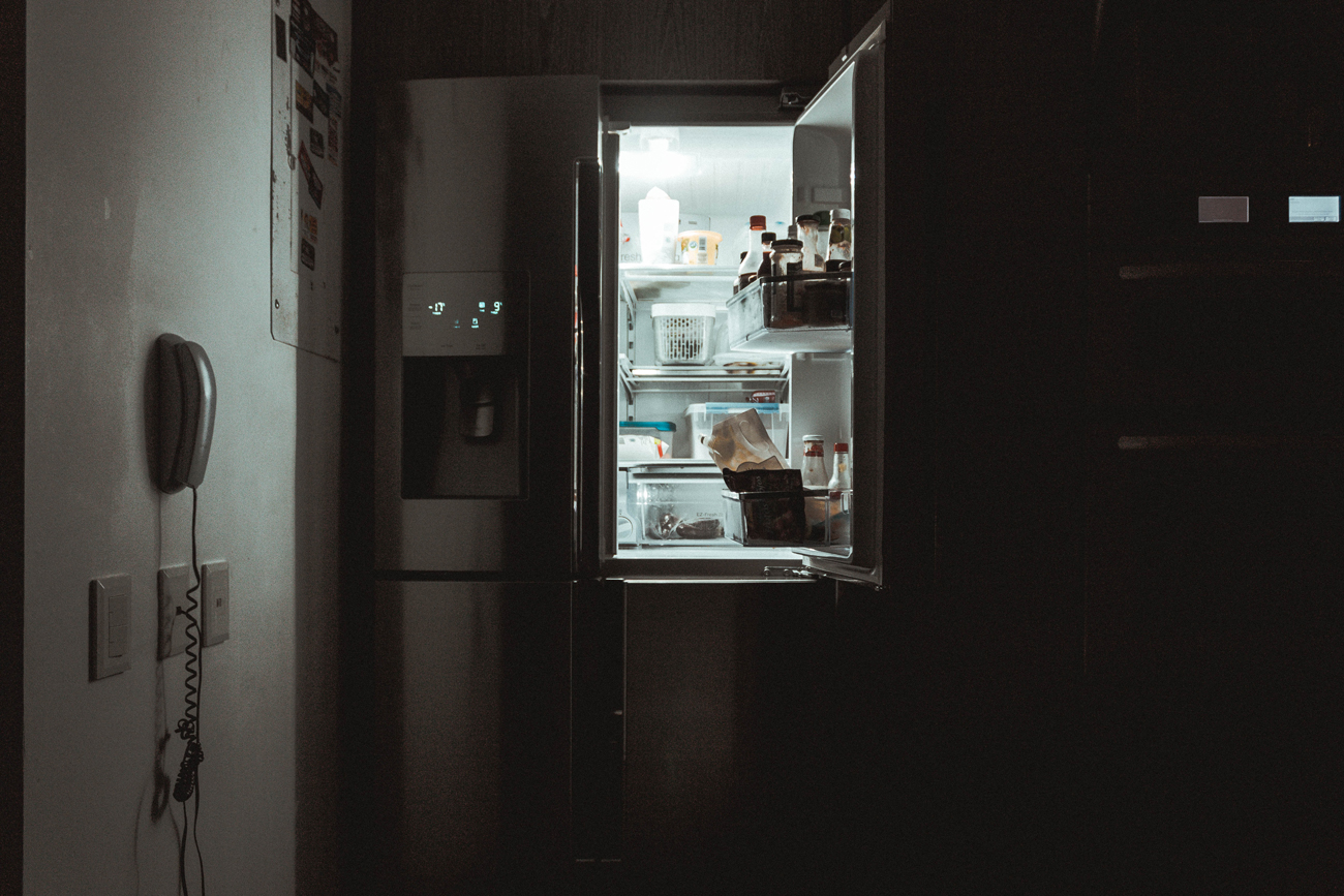 A fridge wit its door open in a dark kitchen